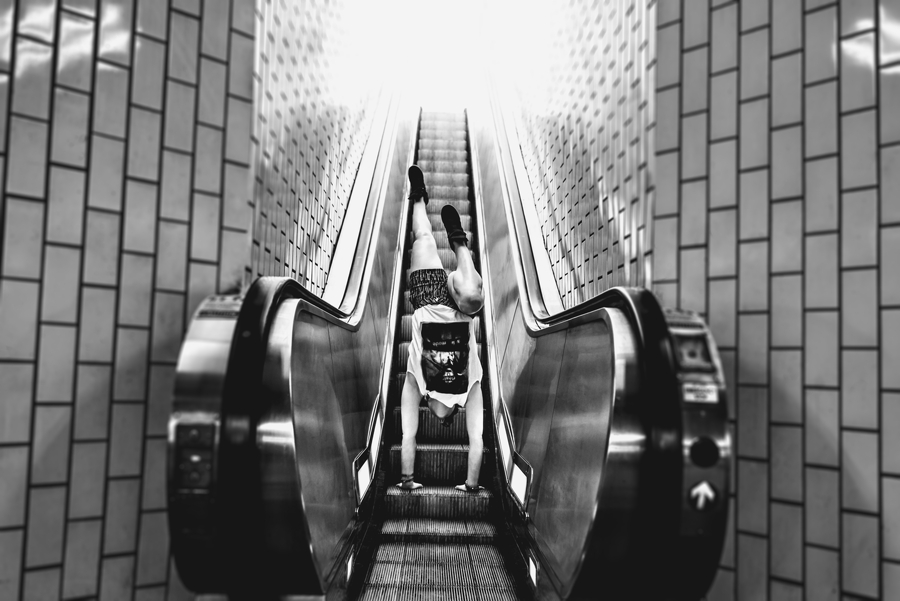 A woman riding the escalator while doing a handstand in philadelphia.
